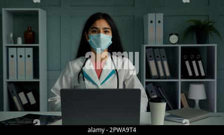 Doktor Frau junge medizinische Mitarbeiterin in Maske sprechen Webcam Konferenz verwenden digitale App verärgert mit niedriger Lautstärke unzuverlässige Internet wi-Fi Verbindung Stockfoto