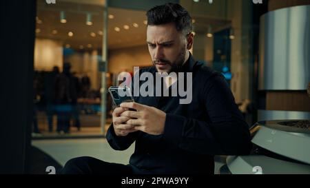 Enttäuscht verärgert verärgerter Geschäftsmann männlicher Angestellter benutzte Telefongerät lesen schlechte Benachrichtigung Falsche Daten Mobilfunkfehler Geschäftsproblem elektronisch Stockfoto