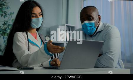 Junge Ärztin Frau sprechen mit altem Mann Patient in Maske verwenden Laptop Check elektronische Gesundheitstest Ergebnis Service Online-Medizin Register ältere Klienten auf Stockfoto