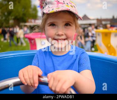 Salisbury, Wiltshire, England, Vereinigtes Königreich, 29. April 2023. Die Temperaturen steigen am Nachmittag bei heißem Sonnenschein auf der Downton Cuckoo Fair, die jedes Jahr am Feiertagswochenende im Mai stattfindet, um die Ankunft des Frühlings zu feiern. Die 4-jährige Jemima ist glücklich, auf den Teetassen zu reiten. Kredit: Paul Biggins/Alamy Live News Stockfoto