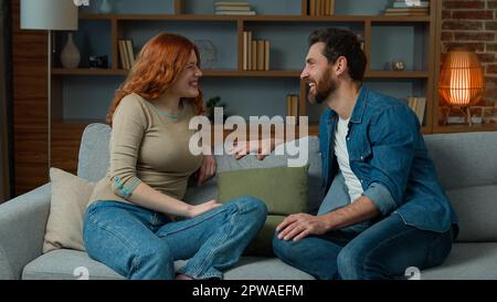 Kaukasisches hispanisches Paar Verwandte Freunde verheiratete Familienfreundin Frau und Freund Mann teilen Nachrichten und reden drinnen sitzen auf dem Sofa Komfortsofa Stockfoto