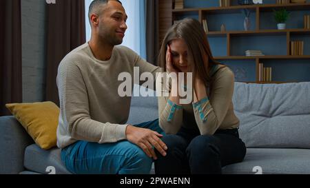 Ein schuldiger afroamerikanischer Mann entschuldigt sich bei einer weinenden Frau, die sich um ihren Ehemann kümmert, ruhig, gestresst, gestresste Frau, tröstete Freundin, die sich entschuldigt Stockfoto