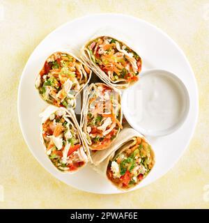 Tortilla mit Hähnchen und frischem Gemüse auf einem Teller mit hellem Hintergrund. Draufsicht, flach liegend Stockfoto