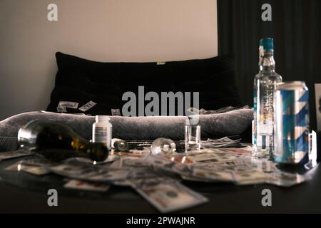Szene mit Sofa und Tisch verstreute alkoholische Getränke, Pillen, Nadel, Drogen. Geld und Karten. Betäubungsmittel und Suchtbegriff Stockfoto