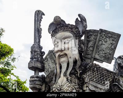 Eine historische chinesische Kriegerstatue aus Stein, die sich im ruhigen buddhistischen Tempel Wat Pho im belebten Bangkok, Thailand, befindet. Die alte Handwerksmannshi Stockfoto