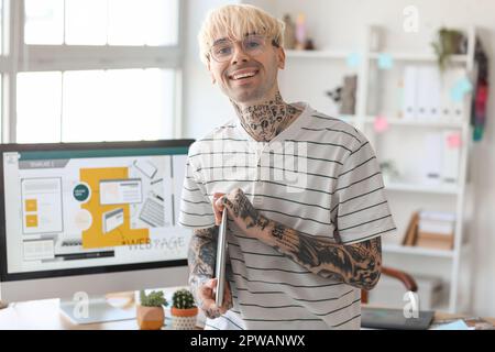 Tätowierter Grafikdesigner mit Laptop im Büro Stockfoto