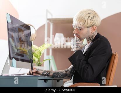 Tätowierter Grafikdesigner, der im Büro am Tisch arbeitet Stockfoto