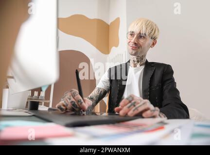 Tätowierter Grafikdesigner, der mit einem Tablet im Büro arbeitet Stockfoto