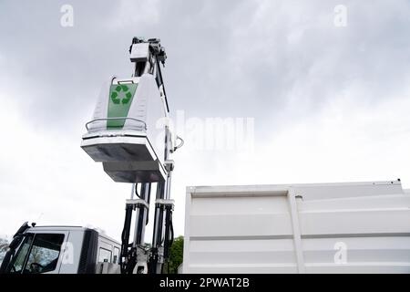 Müllwagen hebt Müllcontainer für recycelbaren Abfall an. Hochwertiges Foto Stockfoto