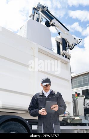 Manager mit einem digitalen Tablet neben dem Müllwagen. Hochwertiges Foto Stockfoto