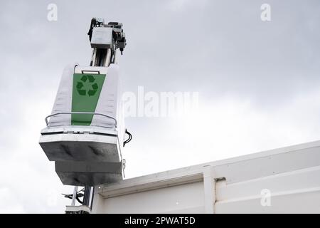 Müllwagen hebt Müllcontainer für recycelbaren Abfall an. Hochwertiges Foto Stockfoto