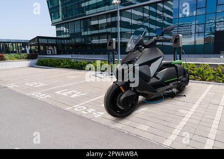 Elektrischer Roller mit Ladestation auf einem Parkplatz für leichte LEV-Elektrofahrzeuge. Stockfoto