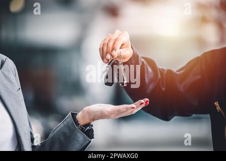 Nahaufnahme männliche Hand, die einen Autoschlüssel für die Finanzierung von Fahrzeugkrediten, Leasing- oder Mietkonzepten ausgibt Stockfoto