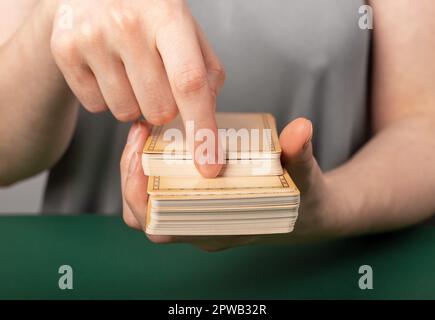 Hände mit Tarotkarten, die das Deck in zwei Teile teilen, um es zu teilen. Stockfoto