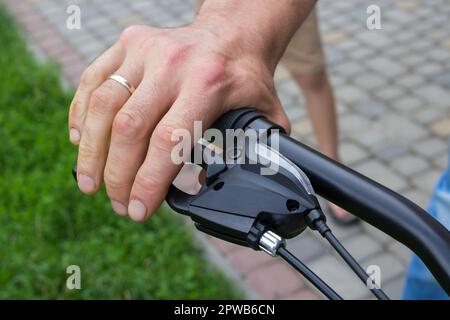 Der man bremst am Motorrad durch Drücken des Bremshebels Stockfoto