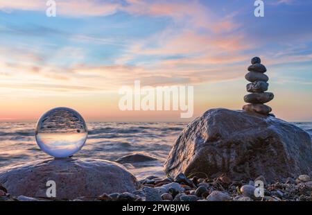 Steinpyramiden und Glaskugel am traumhaften Ostsee-Sandstrand auf Rügen für den spektakulären Sonnenuntergang Stockfoto