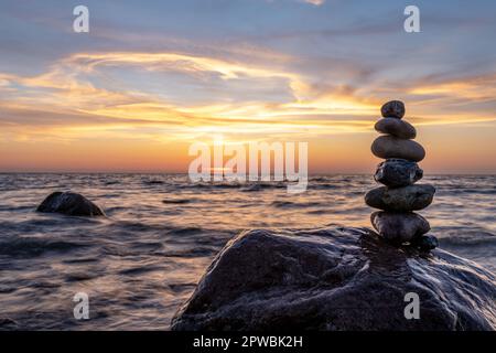 Steinpyramiden und Glaskugel am traumhaften Ostsee-Sandstrand auf Rügen für den spektakulären Sonnenuntergang Stockfoto