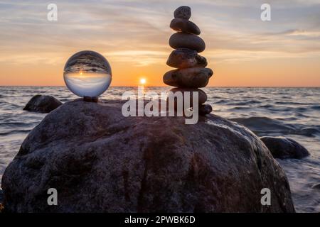 Steinpyramiden und Glaskugel am traumhaften Ostsee-Sandstrand auf Rügen für den spektakulären Sonnenuntergang Stockfoto