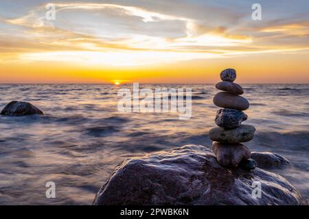 Steinpyramiden und Glaskugel am traumhaften Ostsee-Sandstrand auf Rügen für den spektakulären Sonnenuntergang Stockfoto