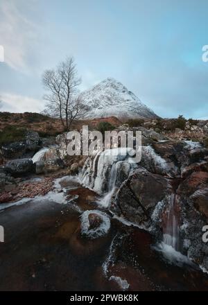 Bergfluss und teilweise gefrorener Wasserfall am Fuße des schneebedeckten Buachaille Etive Mor. Etive Mor Wasserfall. Am Eingang zum Tal von Glencoe in den schottischen Highlands, Schottland Stockfoto