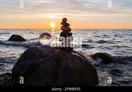 Steinpyramiden und Glaskugel am traumhaften Ostsee-Sandstrand auf Rügen für den spektakulären Sonnenuntergang Stockfoto