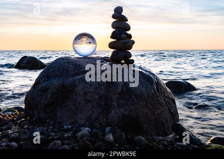 Steinpyramiden und Glaskugel am traumhaften Ostsee-Sandstrand auf Rügen für den spektakulären Sonnenuntergang Stockfoto