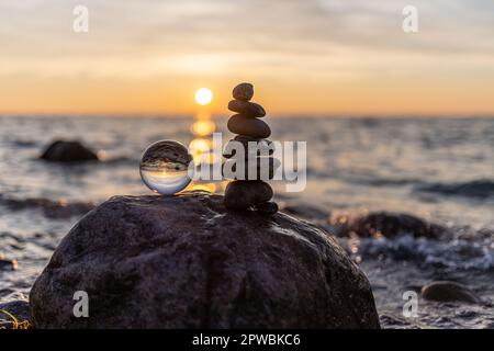 Steinpyramiden und Glaskugel am traumhaften Ostsee-Sandstrand auf Rügen für den spektakulären Sonnenuntergang Stockfoto