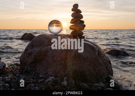 Steinpyramiden und Glaskugel am traumhaften Ostsee-Sandstrand auf Rügen für den spektakulären Sonnenuntergang Stockfoto