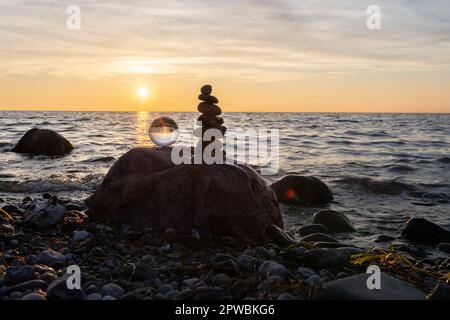 Steinpyramiden und Glaskugel am traumhaften Ostsee-Sandstrand auf Rügen für den spektakulären Sonnenuntergang Stockfoto