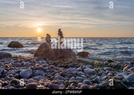 Steinpyramiden und Glaskugel am traumhaften Ostsee-Sandstrand auf Rügen für den spektakulären Sonnenuntergang Stockfoto