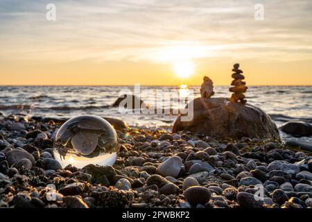 Steinpyramiden und Glaskugel am traumhaften Ostsee-Sandstrand auf Rügen für den spektakulären Sonnenuntergang Stockfoto