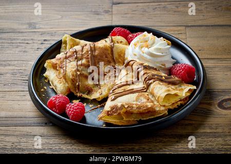 Frisch gebackene Crepes mit Himbeeren und Schlagsahne Stockfoto