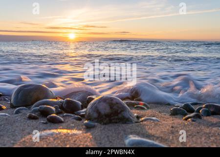 Traumhafter, orangefarbener Sonnenuntergang zwischen Felsen im Meer der Ostsee bei Dranske auf der Insel Rügen Stockfoto