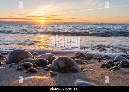Traumhafter, orangefarbener Sonnenuntergang zwischen Felsen im Meer der Ostsee bei Dranske auf der Insel Rügen Stockfoto