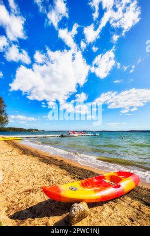 Kleines schwimmendes Kajak am Sandstrand der Küstenstadt Murrays am Lake Macquarie in Australien. Stockfoto