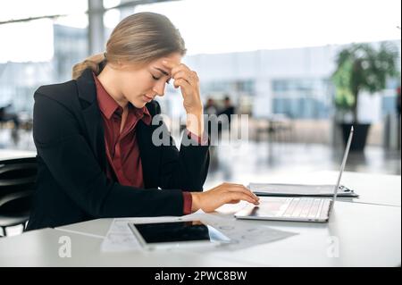 Erschöpft frustriert besorgte Kaukasierin, Mitarbeiterin des Unternehmens, Vertriebsleiterin, sitzt mit geschlossenen Augen am Schreibtisch, fühlt sich müde von der Arbeit, hat Stress, Migräne, hat Probleme mit einem Projekt Stockfoto