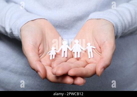 Eine Frau, die Familienfiguren in Papierform hält, Nahaufnahme. Versicherungskonzept Stockfoto