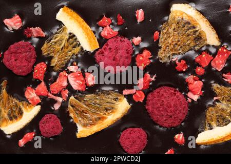 Schokoladenriegel mit gefriergetrockneten Orangen und Beeren als Hintergrund, geschlossen Stockfoto