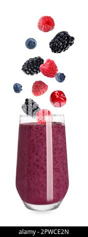 Frische Beeren, die in Glas fallen, mit leckerem Smoothie auf weißem Hintergrund Stockfoto