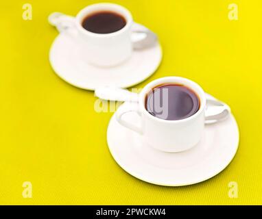Draufsicht auf Tassen frischen Espresso und Löffel platziert Auf Untertassen auf gelbem Hintergrund Stockfoto