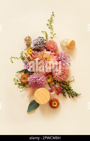 Draufsicht auf natürliche Kosmetikprodukte und frische Blumen arrangiert Auf beigefarbenem Hintergrund Stockfoto