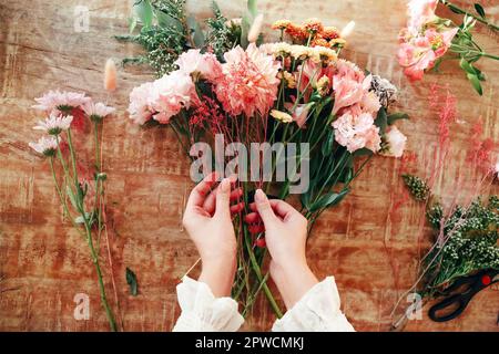 Von oben anonyme weibliche Floristin, die Bouquet aus frischen Blumen auf dem Tisch im kreativen Studio macht Stockfoto