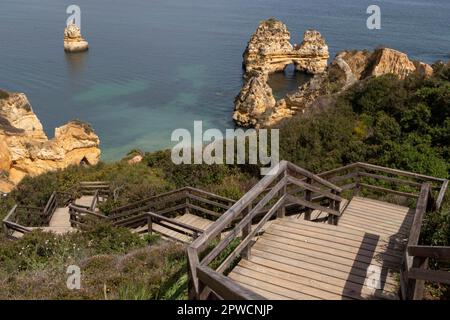 Hölzerne Treppen und Felsformationen am Praia do Camilo an der Küste von Lagos, Bezirk Faro, Algarve, Portugal Stockfoto