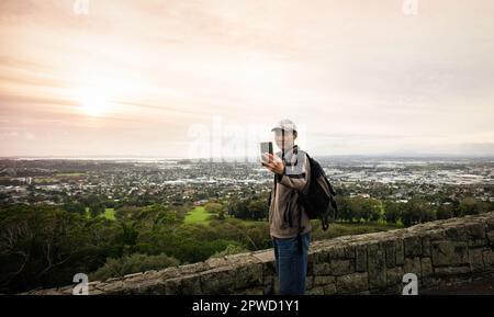 Ein Tourist macht Selfie-Fotos mit dem Smartphone auf dem One Tree Hill. Auckland. Stockfoto