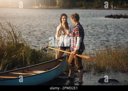Kanufahren, toller Dating-Spaß im Freien. Ein junges Paar, das eine Kanufahrt auf dem See macht. Stockfoto