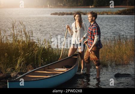 Verlassen Sie diese Komfortzone und gehen Sie Kanufahren. Ein junges Paar, das eine Kanufahrt auf dem See macht. Stockfoto