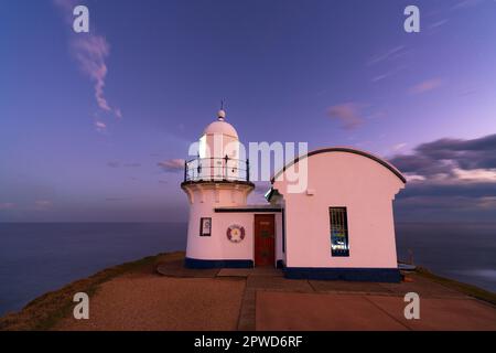 Ein kurzer Leuchtturm und Hüter-Quartiere auf einem Hügel in der Abenddämmerung am Wendepunkt Point Macquarie in New South wales, Australien. Stockfoto