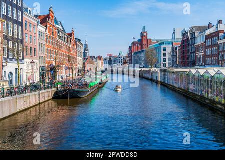 AMSTERDAM, HOLLAND - 17. APRIL 2023: Blick auf einen Kanal in Amsterdam, niederländische Hauptstadt, bekannt für sein aufwändiges Kanalsystem, enge Häuser und Radfahren Stockfoto