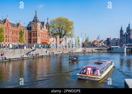 AMSTERDAM, HOLLAND - 17. APRIL 2023: Touristen genießen eine Bootsfahrt entlang eines Kanals in Amsterdam, niederländische Hauptstadt Stockfoto