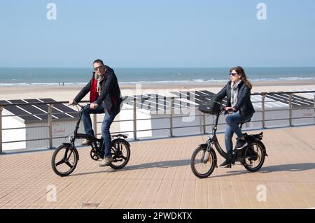 Menschen, die an der Strandpromenade in Ostende, Belgien, entlang der Nordsee Sport treiben und spazieren gehen. Stockfoto